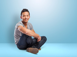 handsome young asian man sitting on a blue room