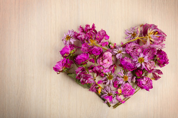 Dried flowers in shape of heart on wooden background