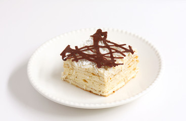 isolated slice of decorated with chocolate napoleon cake, served on white plate