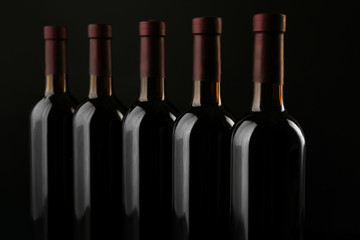 Wine bottles in a row on black  background, close up