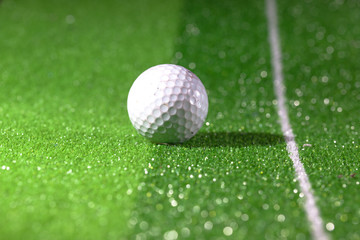 Golf ball placed on the green field with dramatic shadows