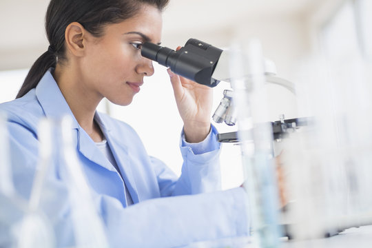 Hispanic scientist using microscope in laboratory