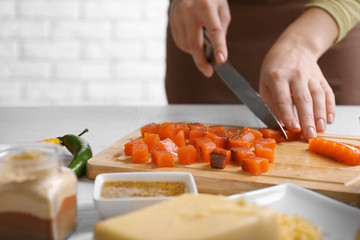 Woman cutting smoked salmon for salad, at kitchen