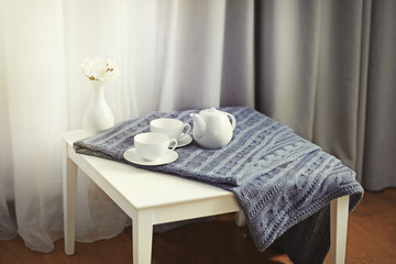 Little table in the room in front of window with curtains