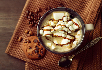 Mug of hot chocolate with marshmallows, on wooden background