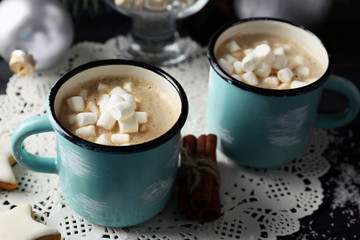 Two mugs of hot cacao with marshmallow on black table