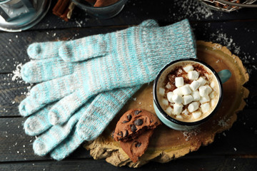 Mug of hot cacao with marshmallow and lantern on black table