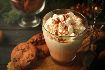 Cup of hot cacao with marshmallow and cookies on black table