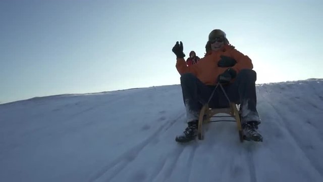 4k footage, four active seniors enjoying wonderful sunny winter day outdoors in snow, one couple having fun tobogganing
