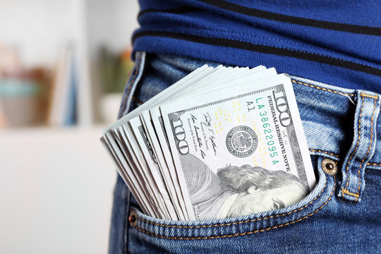 Dollars in jeans pocket on unfocused background closeup