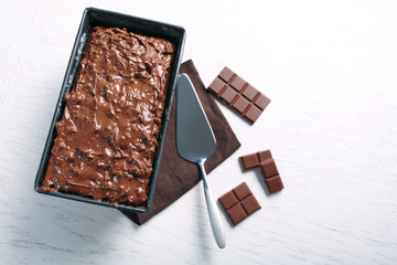 Tasty cake in pan and chocolate on white wooden table, close up