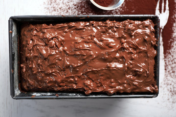 Delicious cake in pan decorated with chocolate and cocoa on white wooden table, close up