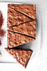 Delicious sliced chocolate cake with nut cream on white plate, close up