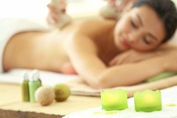 Obraz na płótnie Canvas Spa concept. Someone do relaxing massage with herbal balls to beautiful woman, unfocused