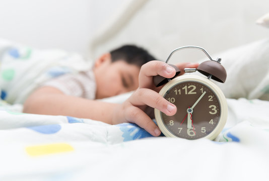 Hand boy reaching out for alarm clock
