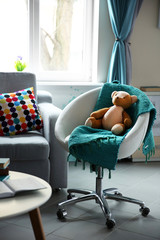Modern living room interior in grey tones with bright blue plaid and teddy bear on chair