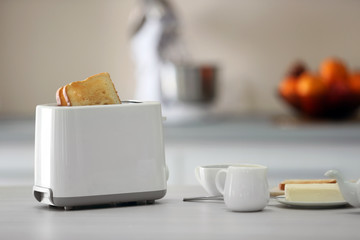 Toaster with dishes on a light kitchen table, close up