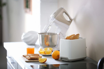 Toaster with mixer and oranges on a light kitchen table