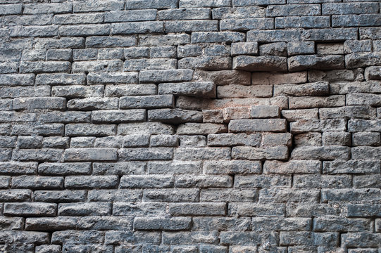 Ancient grey brick wall damaged