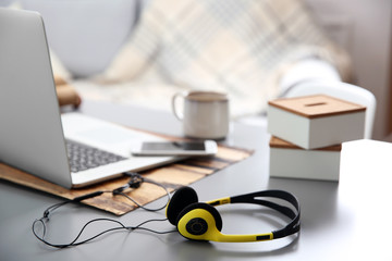 Headphones, phone and laptop on white table against defocused background