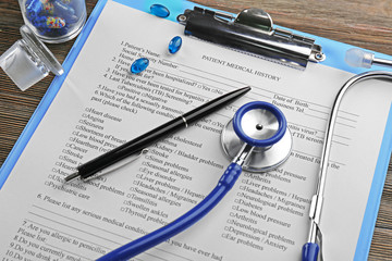 Medical stethoscope, clipboard, pills and pen on the table