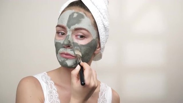 Woman applying with brush clay mud mask to her face 4K