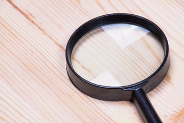 Magnifying glass on wood background,