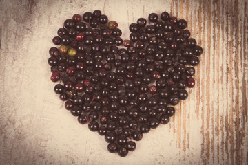 Vintage photo, Heart of fresh elderberry on old wooden background, symbol of love