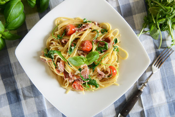 Spaghetti pasta with rucola, cherry tomatoes and prosciutto ham