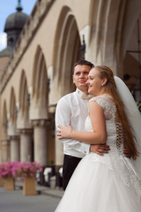 Fototapeta premium To the bright future. Young groom looking away thoughtfully hugging happy smiling bride