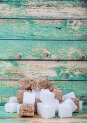 White sugar and brown sugar cane cube over wooden background