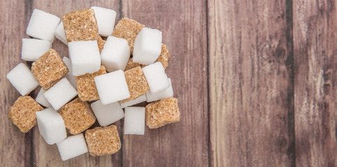 White sugar and brown sugar cane cube over wooden background