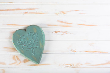A green wooden heart on a white wooden table