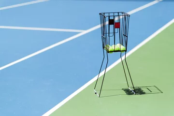 Poster Tennis court with a ball basket and tennis balls in it © NDABCREATIVITY
