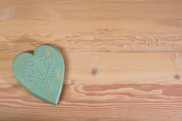 A green wooden heart on a natural wooden table