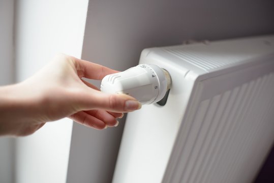 Closeup on woman hand adjusting temperature by thermostat