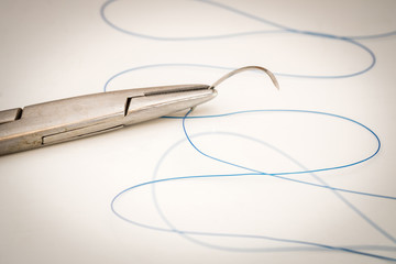 Close up of needle holder with suture and needle