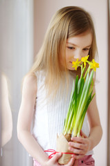 Adorable smiling little girl holding daffodils