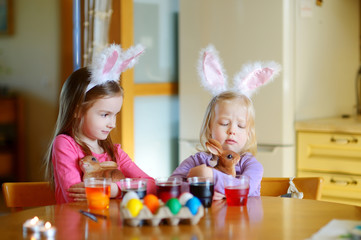 Two little sisters painting colorful Easter eggs