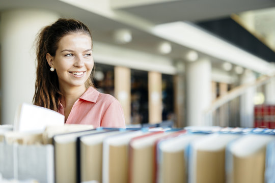 Woman choosing a book from the shelf in a library