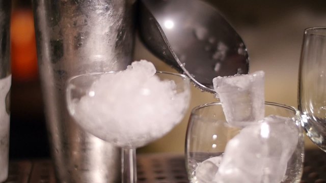 Bartender putting ico on glass, slowmotion shoot