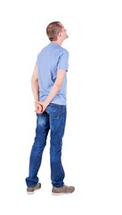 Fototapeta premium Back view of young man in t-shirt and jeans looking.
