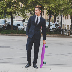 Young handsome Asian model posing with his skateboard