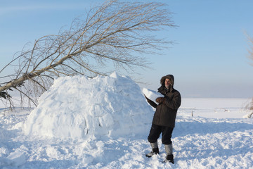 The man  building an igloo on a snow glade in the winter