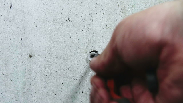DIY, close up of man's hand removing stubborn old wall plug (rawlplug)  from an interior wall  using pliers while renovating and redecorating a house.