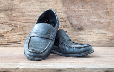 Still life with black leather old shoes on wood background