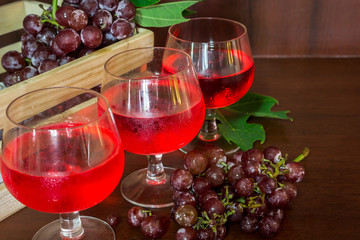 Glasses of wine and  grapes in wooden crate on wooden background