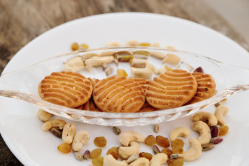 cookies on plate with dry fruits on grey wooden background
