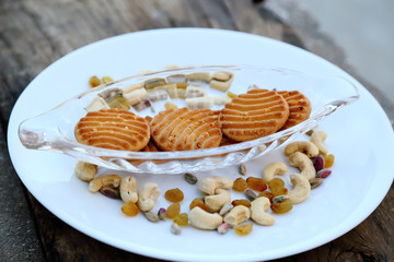 cookies on plate with dry fruits on grey wooden background