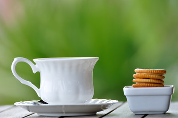 Classic white tea cup and crackers with blur background.